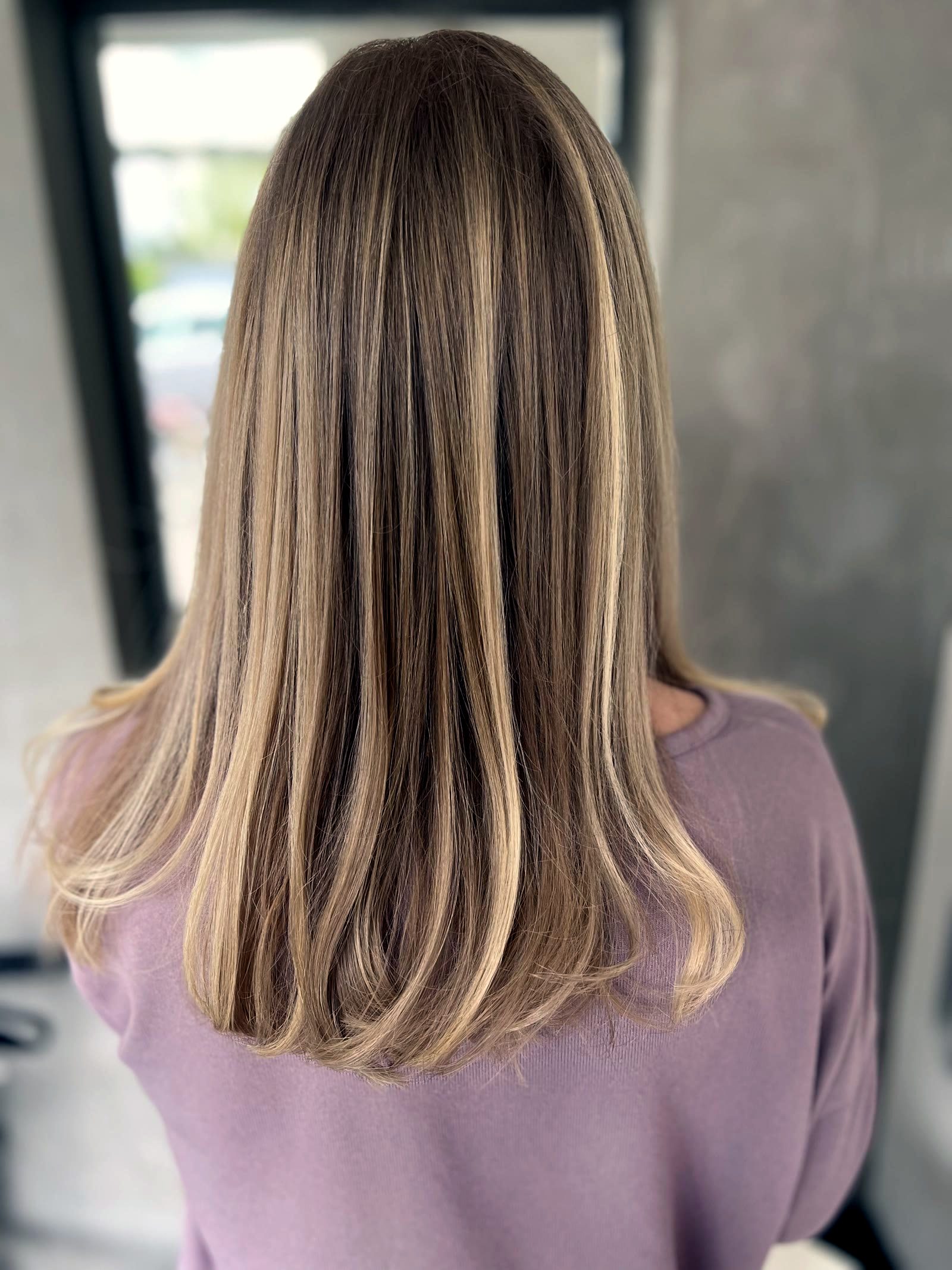 Langes blondes Haar von hinten mit weichen, natürlichen Farbverläufen nach einer Balayage.